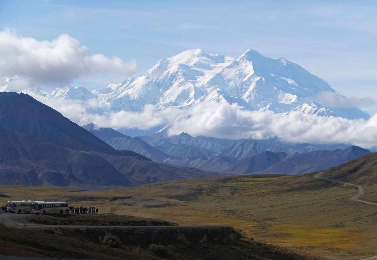 In this Aug. 26, 2016, file photo sightseeing buses and tourists are seen at a pullout popular for taking in views of North America's tallest peak, Denali, in Denali National Park and Preserve, Alaska. 