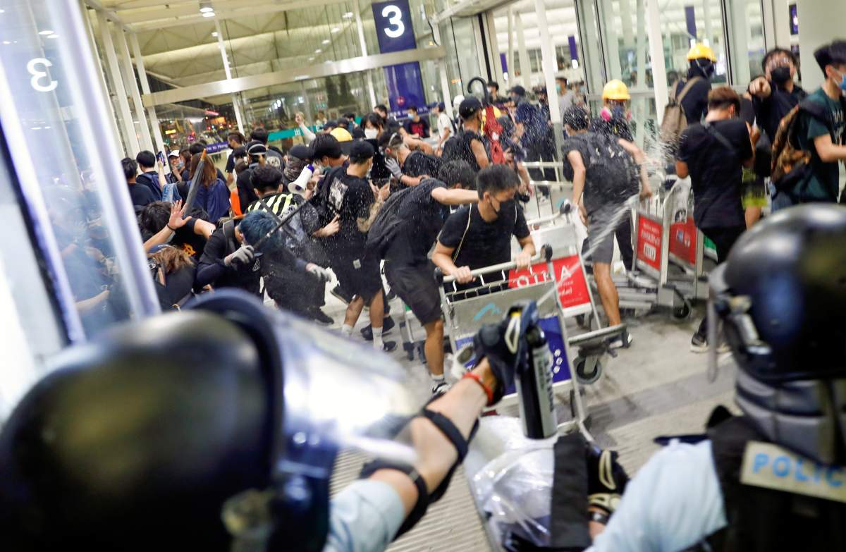 Riot police use pepper spray to disperse anti-extradition bill protesters during a mass demonstration after a woman was shot in the eye, at the Hong Kong international airport, in Hong Kong China August 13, 2019.