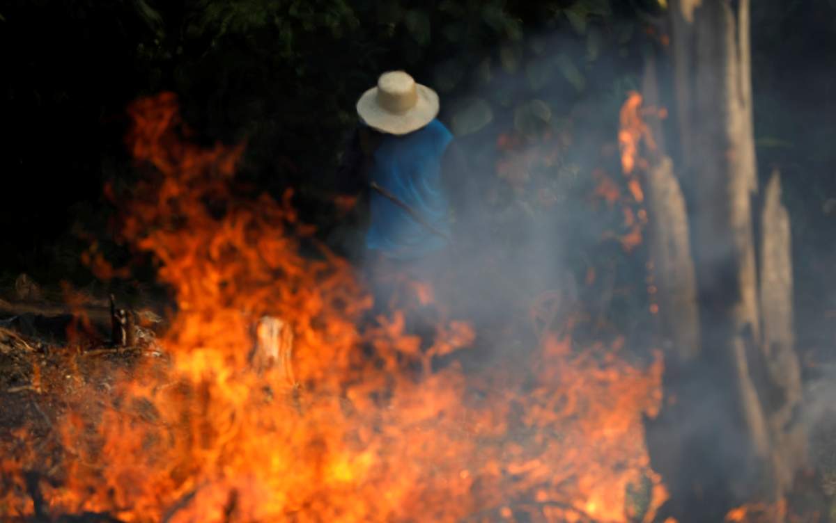 A man works in a burning tract of Amazon jungle as it is being cleared by loggers and farmers in Iranduba, Amazonas state, Brazil August 20, 2019. REUTERS/Bruno Kelly/File Photo