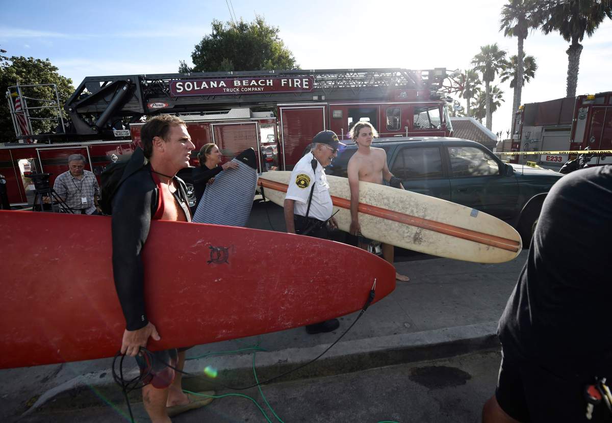 Surfers wait at the top of the stairs above the site of a cliff collapse at a popular beach Friday, Aug. 2, 2019, in Encinitas, Calif. At least one person was reportedly killed, and multiple people were injured, when an oceanfront bluff collapsed Friday at Grandview Beach in the Leucadia area of Encinitas, authorities said.