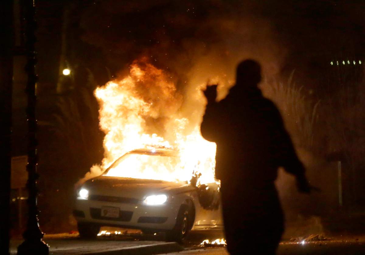 In this Nov. 24, 2014, file photo, a police car is set on fire amid protests that followed the announcement that a grand jury had declined to indict Ferguson police officer Darren Wilson in the death of Michael Brown.