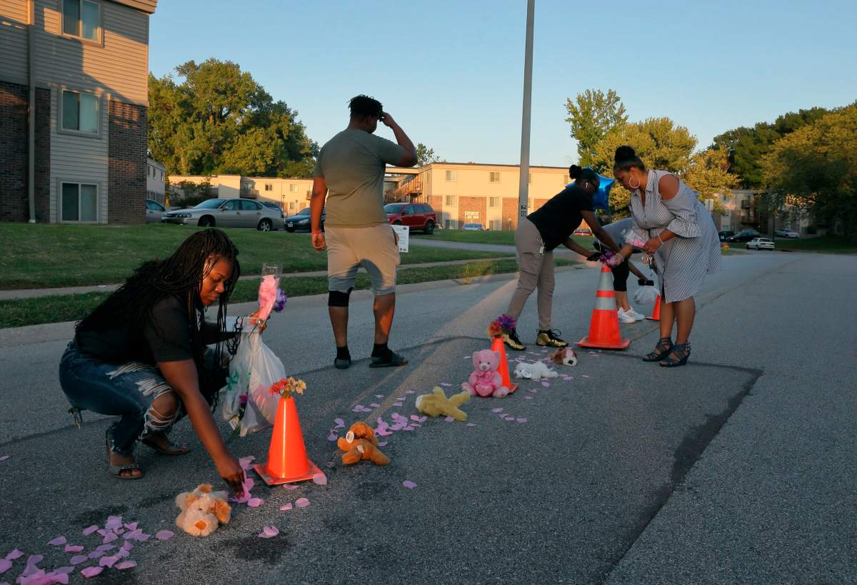 Cori Bush, left, drops paper rose petals around a memorial to Michael Brown on Canfield Drive in Ferguson, Mo., as she and others members of the community rebuild the memorial where Brown was shot and killed by Ferguson Police officer Darren Wilson, on Wednesday, Aug. 7, 2019. 