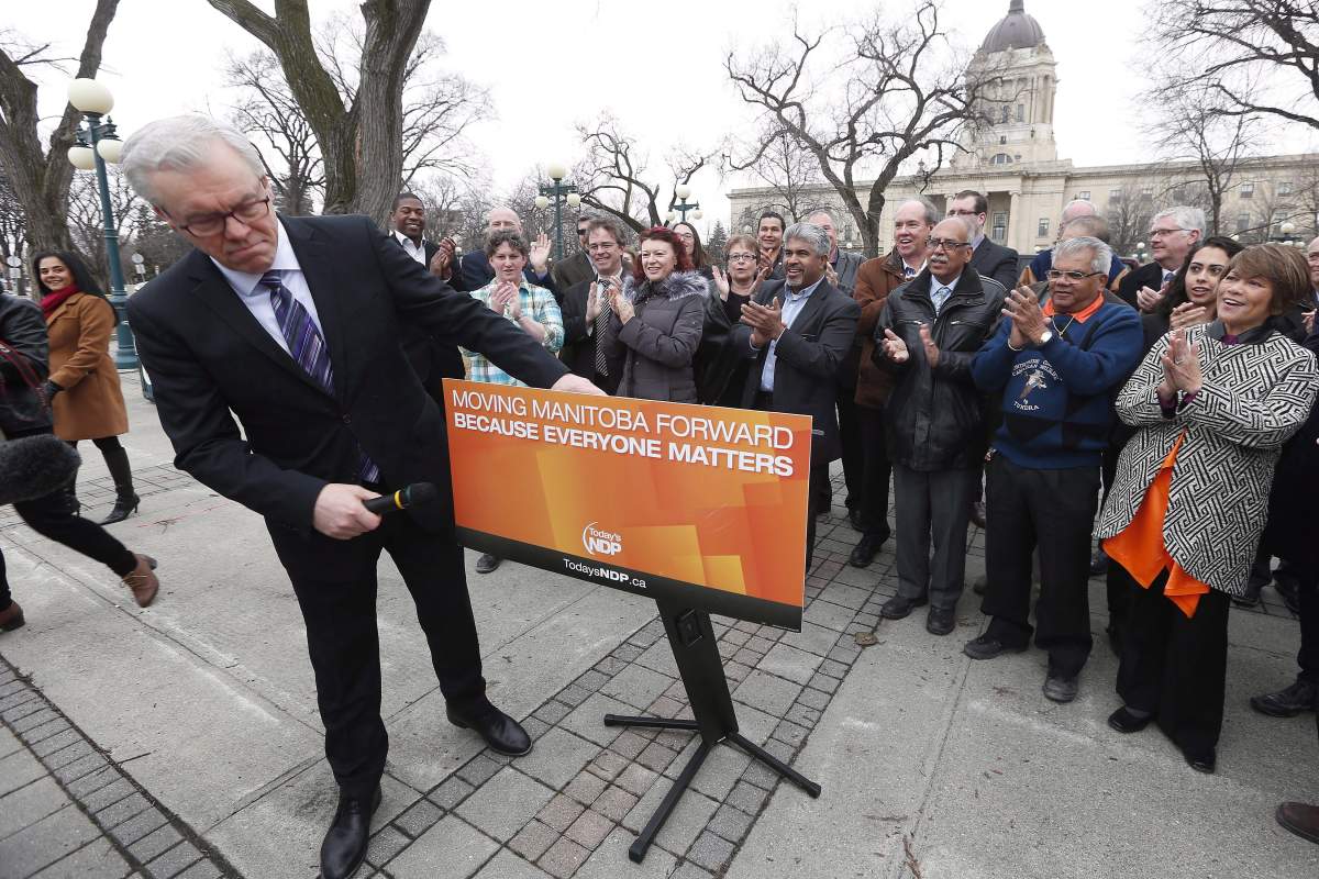 Then Manitoba premier and NDP leader Greg Selinger checks his sign before speaking to the media after asking the Lieutenant Governor of Manitoba to call the 2016 provincial election. The slogan on the party’s podium is now being used by the Progressive Conservatives.