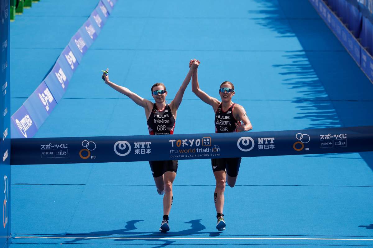 Britain's Georgia Taylor-Brown, left, and Jessica Learmonth hold hands as they cross the finish line during a women's triathlon test event at Odaiba Marine Park, a venue for marathon swimming and triathlon at the Tokyo 2020 Olympics, Thursday, Aug. 15, 2019, in Tokyo. 