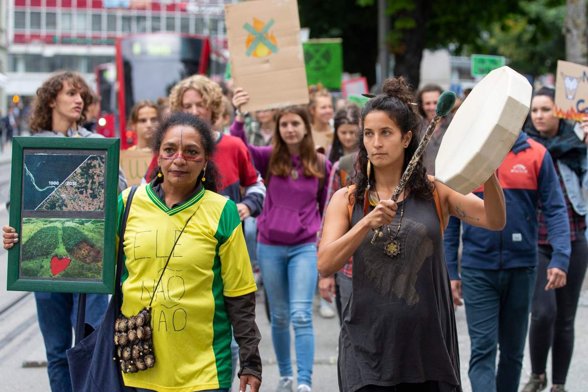 People protest in Bern, Switzerland, Friday, Aug. 23, 2019 against the burning down of the Amazonas rainforest and the politic of Brazilian President Jair Bolsonaro. (Peter Klaunzer/Keystone via AP)