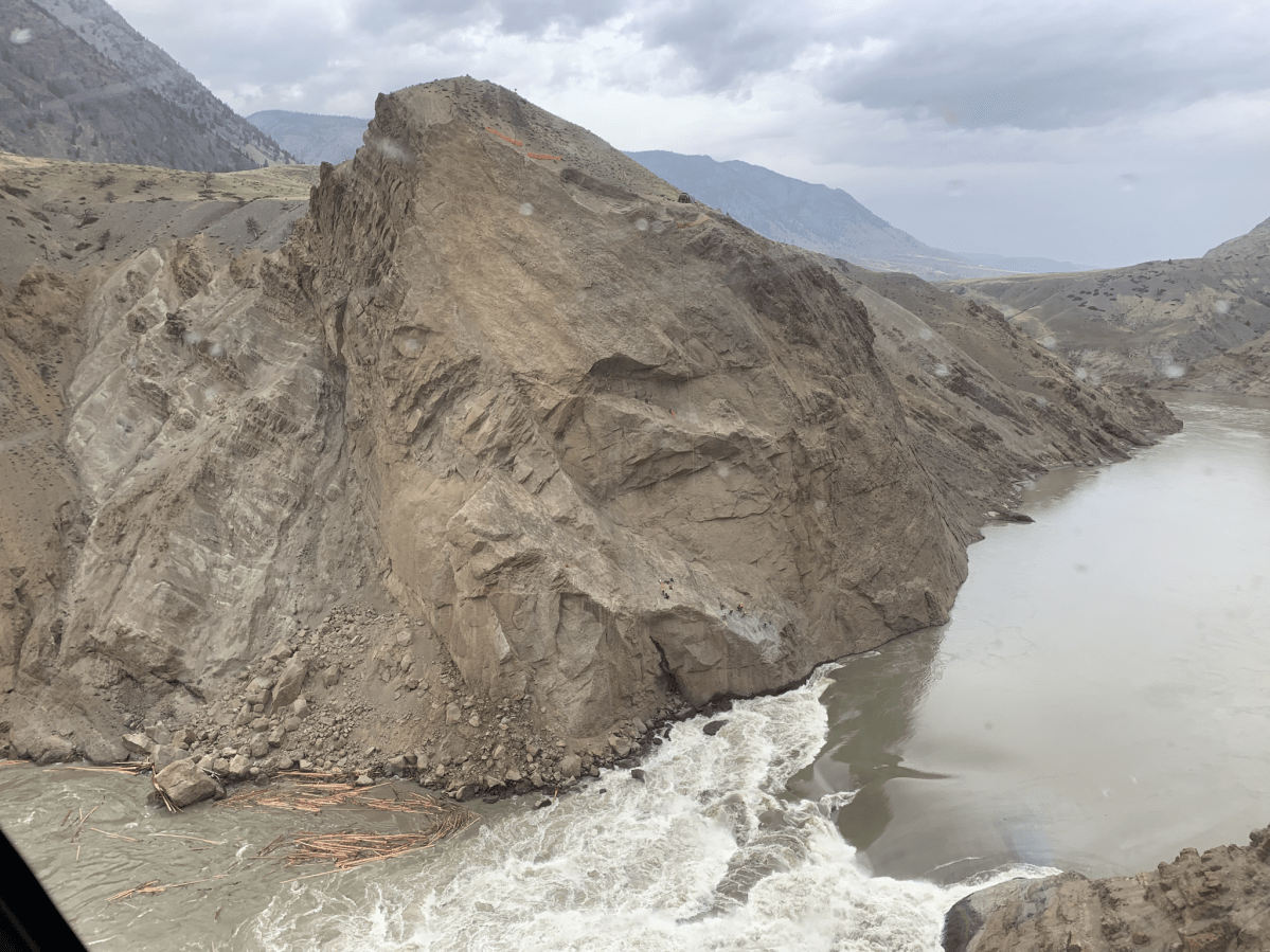 Crews appear ant-like as they work on a treacherous cliff above a rushing waterfall caused by the Big Bar landslide. 