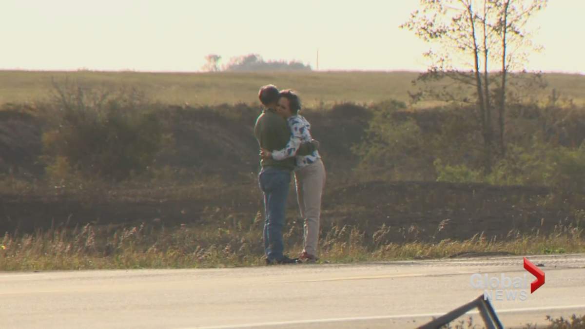 Friends of a Saskatoon couple killed in a crash near Cereal, Alta., embrace as they pay their respects at the crash site.