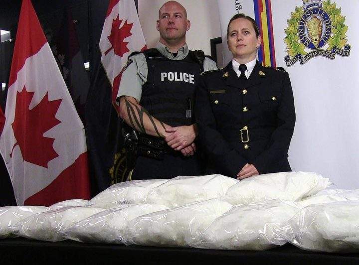 RCMP Cpl. Jon Cormier and RCMP Insp. Charlene O’Neill stand over seized methamphetamine from a truck at a Canada-U.S. border crossing in southern Alberta during a press conference in Calgary on Thursday, August 1, 2019.
