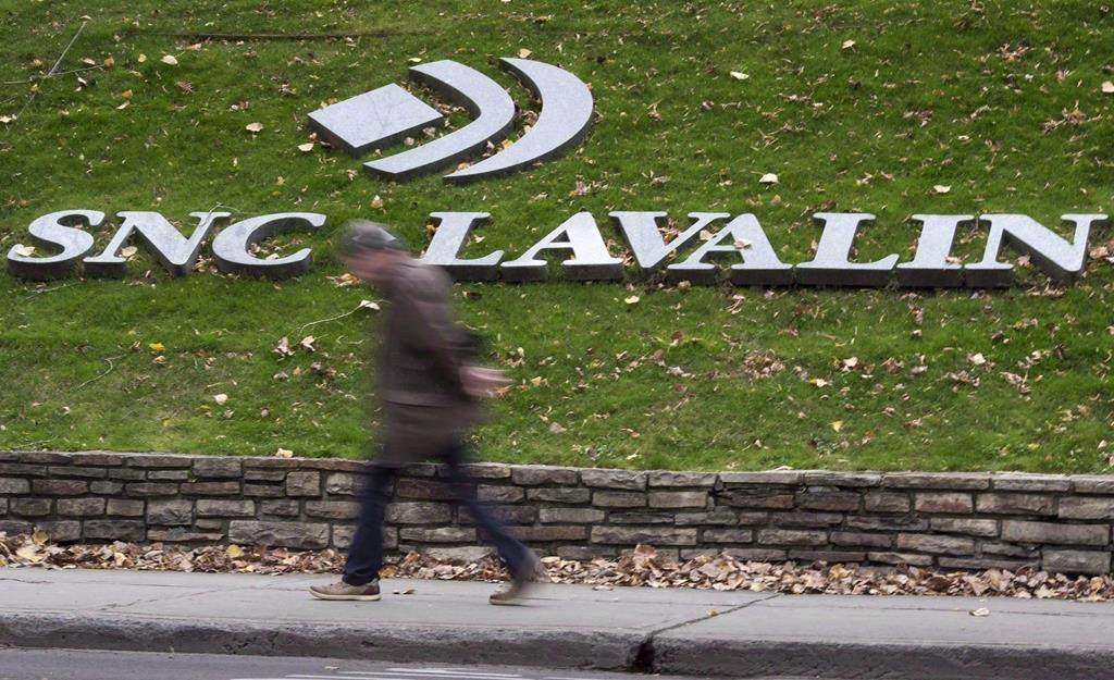 The downgrade comes with the company already in the crosshairs of a political controversy and on the brink of a criminal trial on corruption charges connected to business dealings in Libya.
