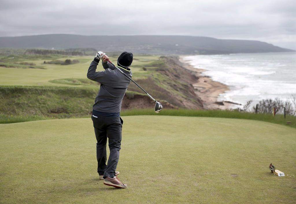 A golfer hits from the tee on the 528 yard, par 5, 18th hole at Cabot Cliffs, the seaside links golf course in Inverness, N.S. on June 1, 2016.