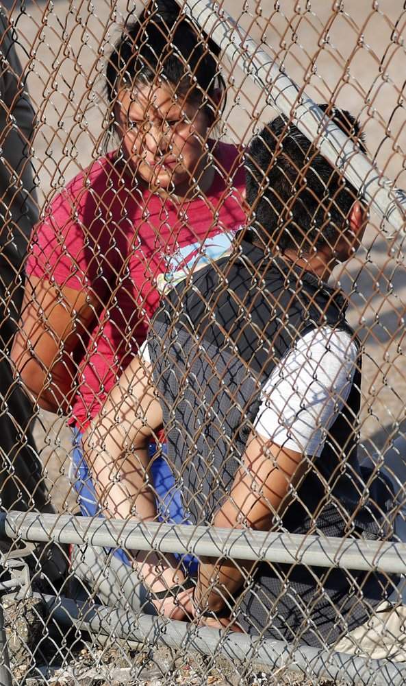 A handcuffed woman stares though the chain link fencing at Koch Foods Inc., in Morton, Miss., Wednesday, Aug. 7, 2019.