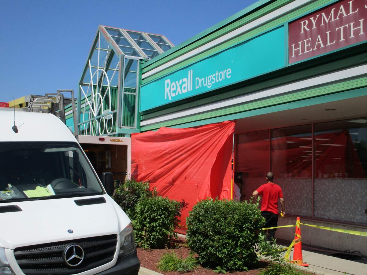Workers begin repair on a window police say was smashed when suspects drove a pick-up into a Mountain pharmacy overnight to steal an ATM.