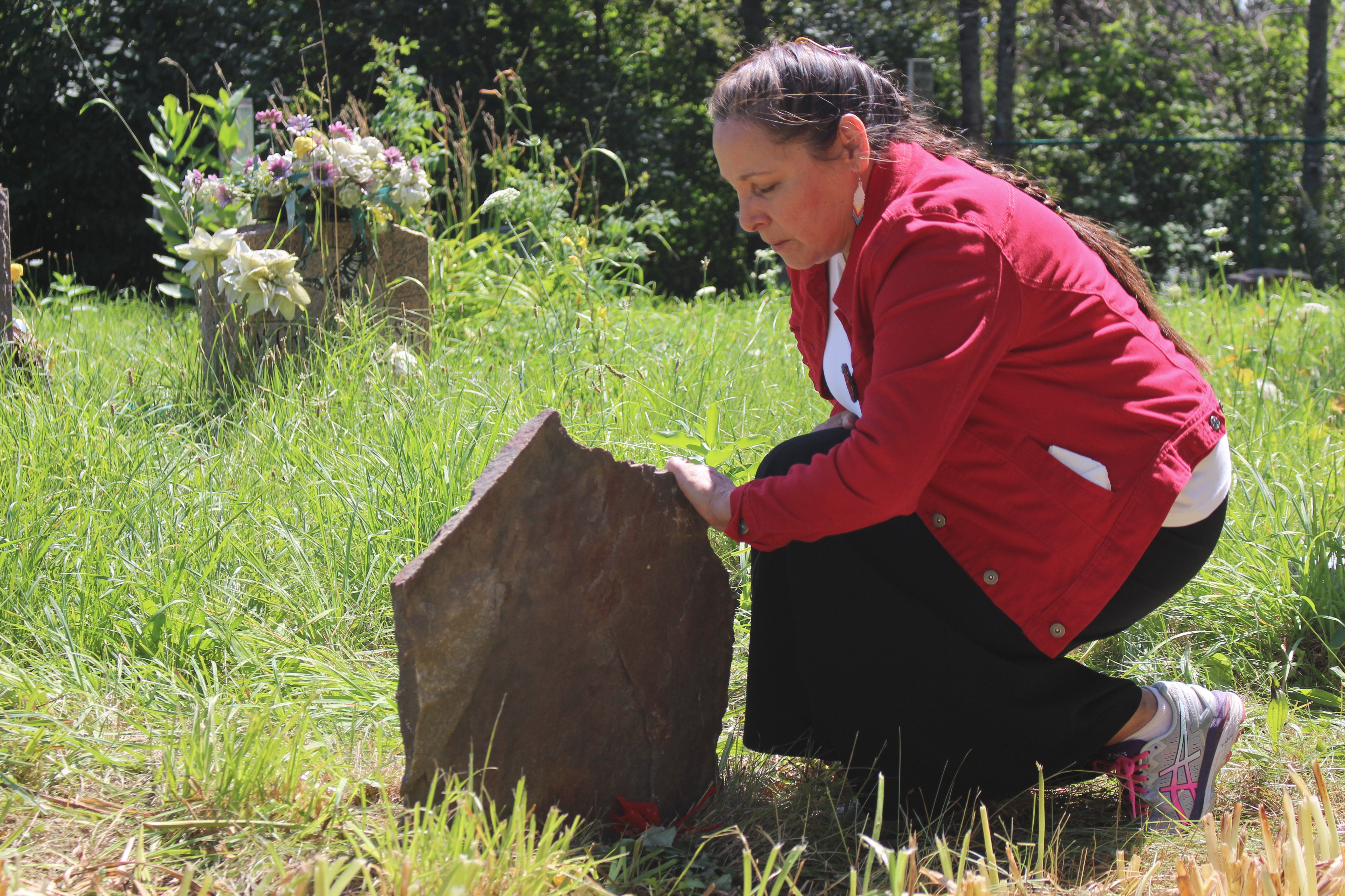 Meggie Cywink places a hand on her sister Sonya’s gravestone on Aug. 20, 2019. Moments before she placed a ceremonial tobacco tie atop her sister’s grave.