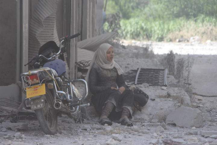 A woman is seen near damaged buildings after Assad regime forces carried out airstrike over de-escalation zone “Jisr al-Shughur” village of Idlib, Syria on July 10, 2019.