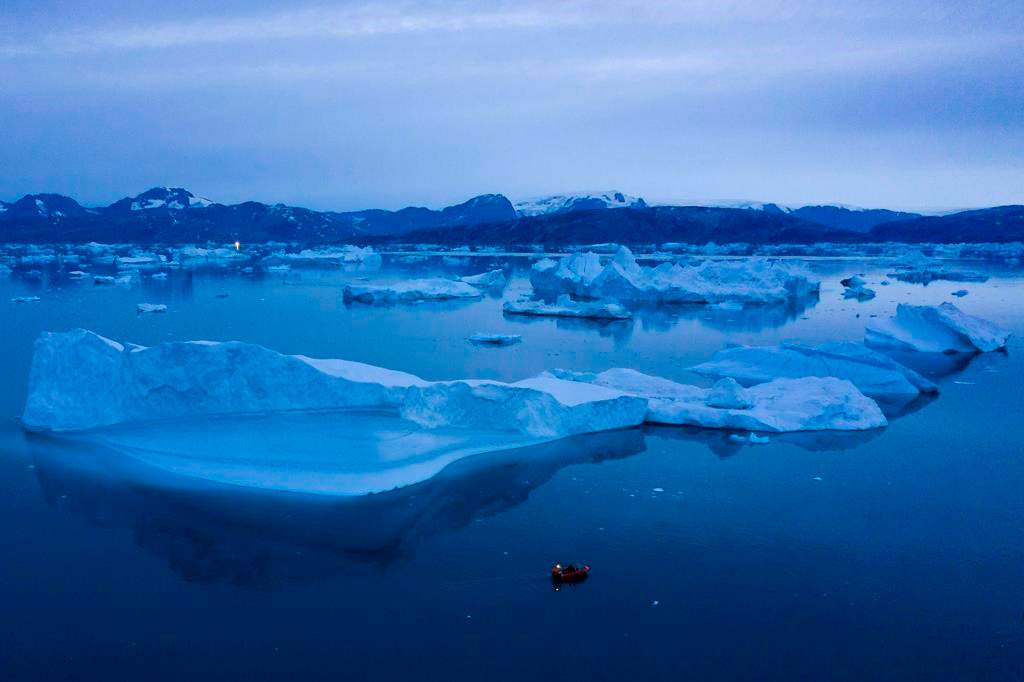 In this Aug. 15, 2019, photo, a boat navigates at night next to large icebergs near the town of Kulusuk, in eastern Greenland. Greenland’s ice has been melting for more than 20 years, but in 2019, it’s as if Earth’s refrigerator door has been left open, and it means a potentially large rise in the world’s sea levels. (AP Photo/Felipe Dana)