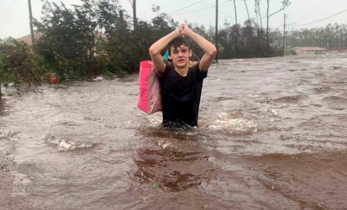 Matthew Aylen wades through waist-deep water as he is rescued from his flooded home during hurricane Dorian in Freeport, Bahamas, Tuesday, Sept. 3, 2019.  (AP Photo/Tim Aylen)