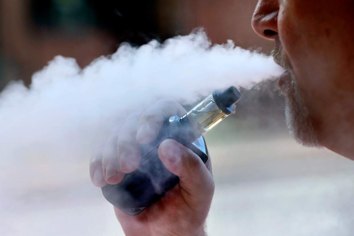 In this Aug. 28, 2019 photo a man exhales while smoking an e-cigarette in Portland, Maine.