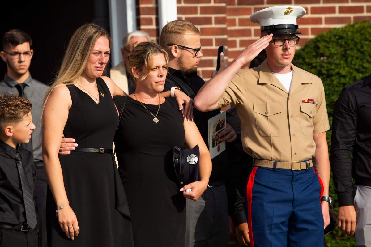 Kiersten Haub, from left, Erika Starke, and Michael Haub, family members of New York firefighter Michael Haub. (AP Photo/Eduardo Munoz Alvarez)