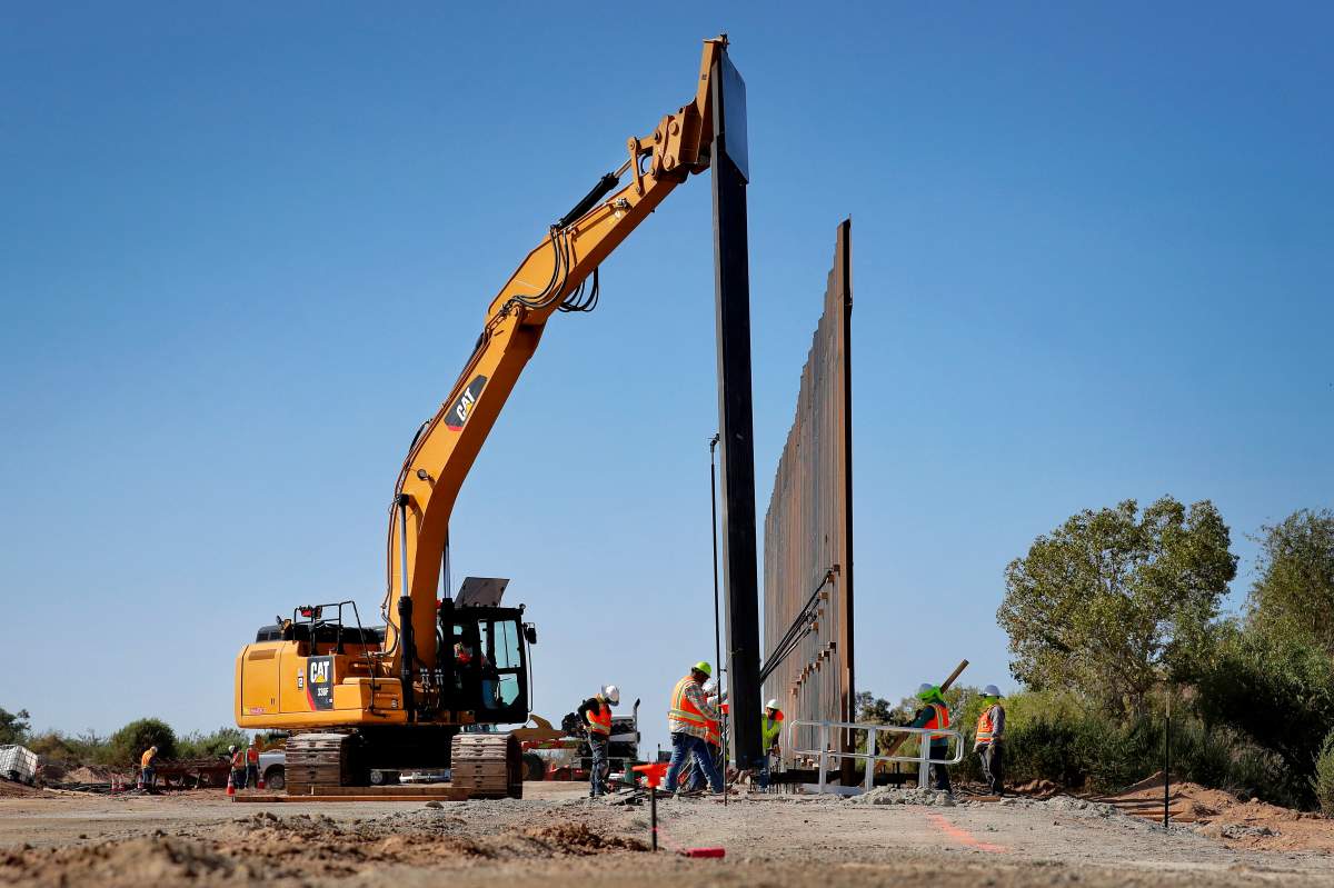 Government contractors erect a section of Pentagon-funded border wall along the Colorado River, Tuesday, Sept. 10, 2019 in Yuma, Ariz. (AP Photo/Matt York)