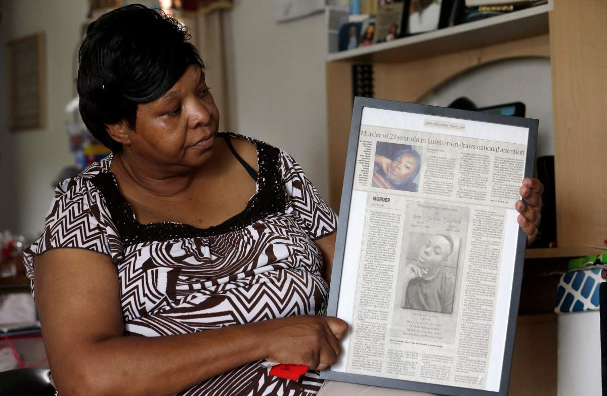 In this photo taken Tuesday, Aug. 6, 2019 Brenda Scurlock is shown in her home in Lumber Bridge, N.C. holding a newspaper clipping about her son's murder. Scurlock's son Avery Scurlock, who used the name Chanel when dressing as a woman in social settings and hoped to have sex reassignment surgery,  was found shot to death in June. This death of a transgender person in North Carolina is one of 18  so far this year, and  17  of the victims have been black women. 