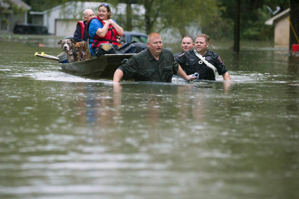 Splendora Police Lt. Troy Teller, left, Cpl. Jacob Rutherford and Mike Jones pull a boat carrying Anita McFadden and Fred Stewart from their flooded neighbourhood inundated by rain from tropical depression Imelda on Thursday, Sept. 19, 2019, in Spendora, Texas. (Brett Coomer/Houston Chronicle via AP)