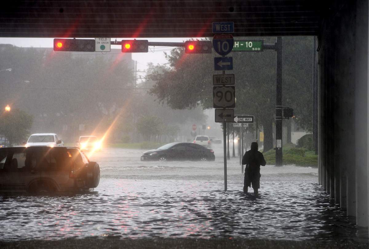 A man makes his way under the I-10 overpass where several roads remained heavily flooded throughout the afternoon, Thursday, Sept. 19, 2019 in Beaumont, Texas. The slow-churning remnants of tropical storm Imelda dangerously flooded parts of Texas and Louisiana on Thursday, leaving at least two people dead and rescue crews and volunteers with boats scrambling to reach scores of stranded drivers and families trapped in their homes. (Kim Brent/The Beaumont Enterprise via AP)