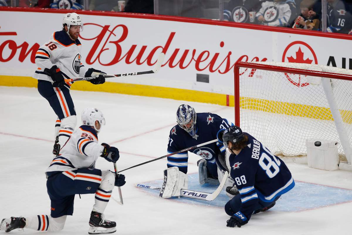 Edmonton Oilers right wing Tomas Jurco (92) scores against Winnipeg Jets goaltender Connor Hellebuyck (37) as defenceman Nathan Beaulieu (88) defends during first period NHL action in Winnipeg on Thursday, September 26, 2019. THE CANADIAN PRESS/John Woods.