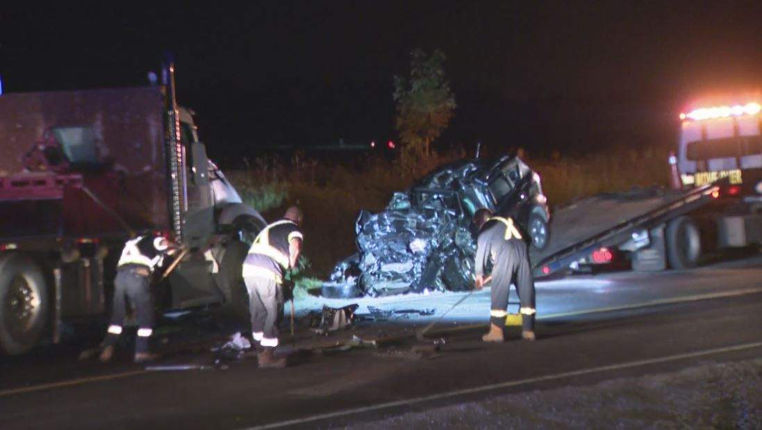Workers prepare to remove one of the vehicles from the scene of the crash.