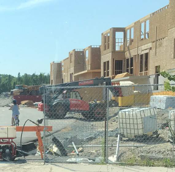 A cyclist is seen riding through a construction site in Halifax Regional Municipality next to heavy machinery.