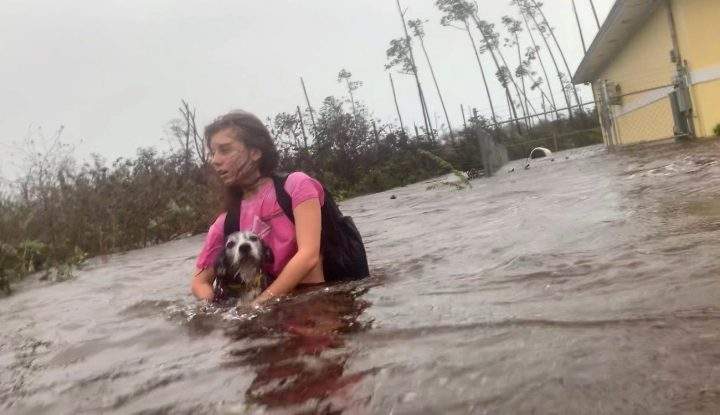 Julia Aylen wades through waist-deep water carrying her pet dog as she is rescued from her flooded home during hurricane Dorian in Freeport, Bahamas, Tuesday, Sept. 3, 2019.