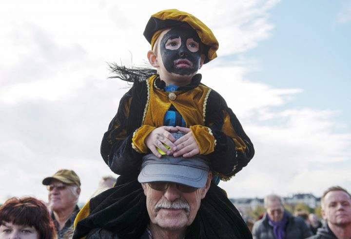 A Dutch child wearing blackface make up is carried during a demonstration in The Hague, Netherlands on Saturday, Oct. 26, 2013.