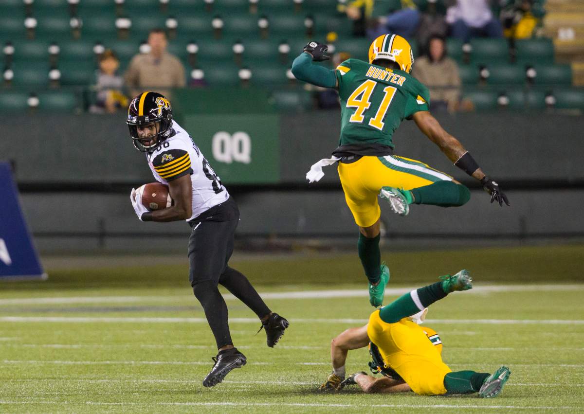 Hamilton Tiger-Cats wide receiver Bralon Addison (86) dodges tackles by Edmonton Eskimos defensive back Monshadrik Hunter (41) and safety Jordan Hoover (28) to run in a touchdown during first half CFL action in Edmonton, Alta., on Friday September 20, 2019.