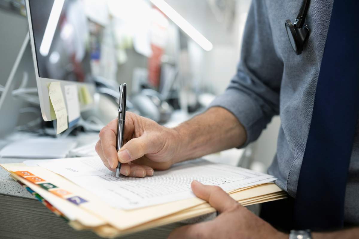 A file photo of a doctor writing in a patient file.