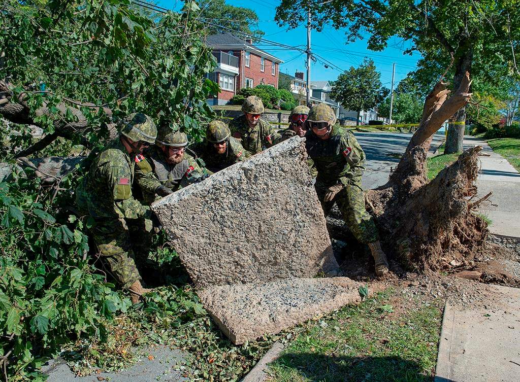 Members of the 4 Engineer Support Regiment from Canadian Forces Base Gagetown move a slab of sidewalk as they assist in the cleanup in Halifax on Monday, Sept. 9, 2019.