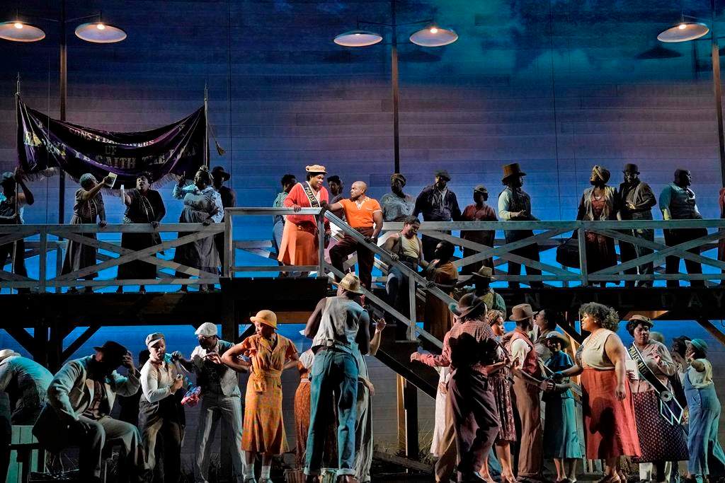 This image released by the Metropolitan Opera shows Latonia Moore as Serena, center left on stairs, and Frederick Ballentine as Sportin' Life in a scene from the Gershwins' "Porgy and Bess." (Ken Howard/Met Opera via AP).