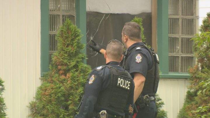 Regina police officers investigate a broken window caused by what appears to be a bullet on Sept. 3, 2019.