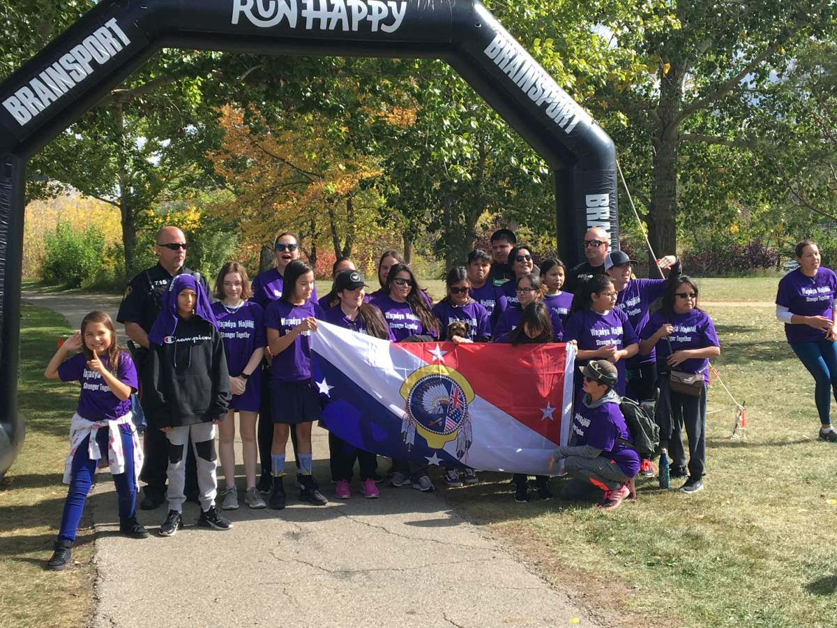 Participants in the 9th Annual Race Against Racism pose for a photo with a Saskatoon police officer.