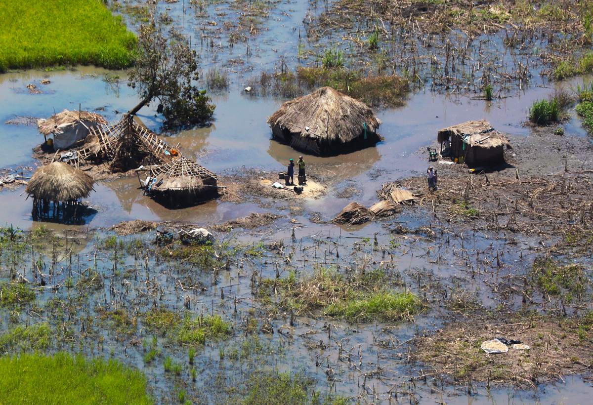 In this Tuesday March 26, 2019 file photo, a family stand outside their submerged huts near Beira, Mozambique.