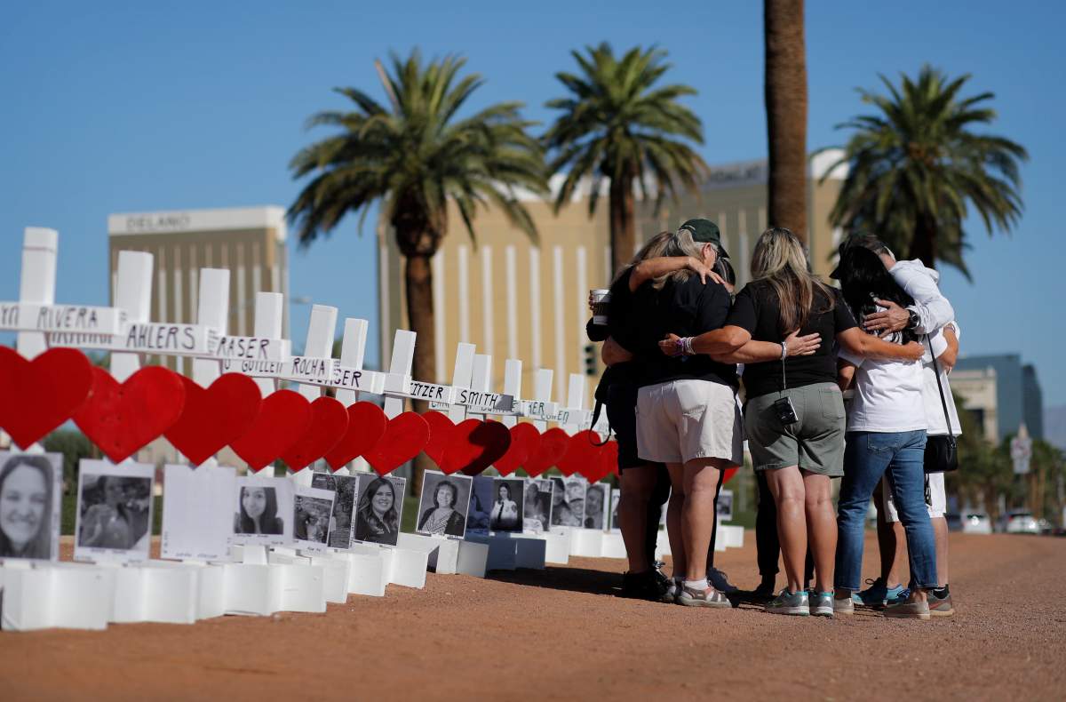 People pray at a makeshift memorial for shooting victims, Tuesday, Oct. 1, 2019, in Las Vegas, on the anniversary of the mass shooting two years earlier. (AP Photo/John Locher)
