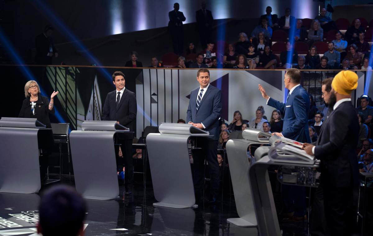 Green Party leader Elizabeth May, left, and People’s Party of Canada leader Maxime Bernier, third from right, exchange ideas as Liberal leader Justin Trudeau, Conservative leader Andrew Scheer, Bloc Quebecois leader Yves-Francois Blanchet and NDP leader Jagmeet Singh look on during the Federal leaders debate in Gatineau, Que. on Monday, October 7, 2019. THE CANADIAN PRESS/Justin Tang