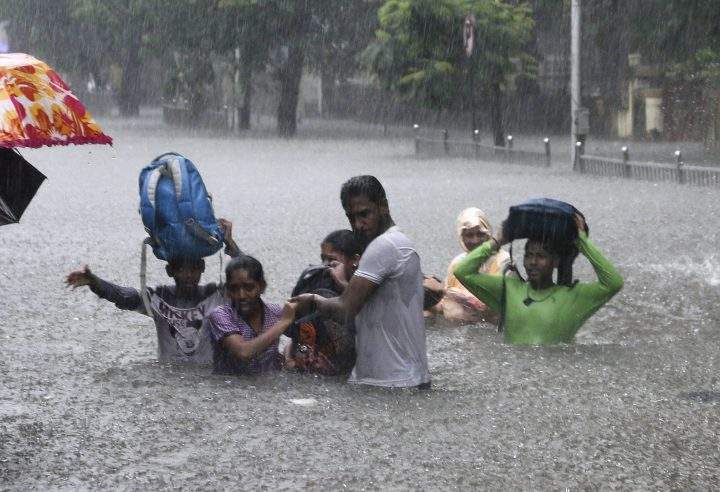 In this Sept. 4, 2019, file photo, people hold hands and navigate their way through a flooded street as it rains in Mumbai, India.