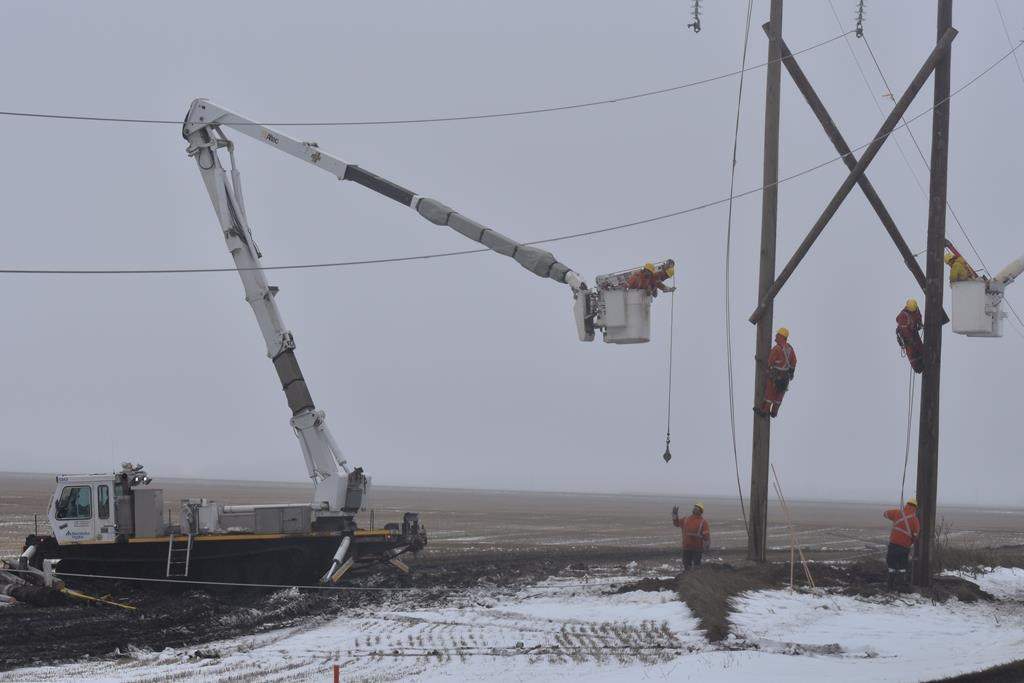 Workers use a tracked vehicle to repair a damaged hydro pole in Portage La Prairie, Man., in a Tuesday, Oct. 15, 2019.