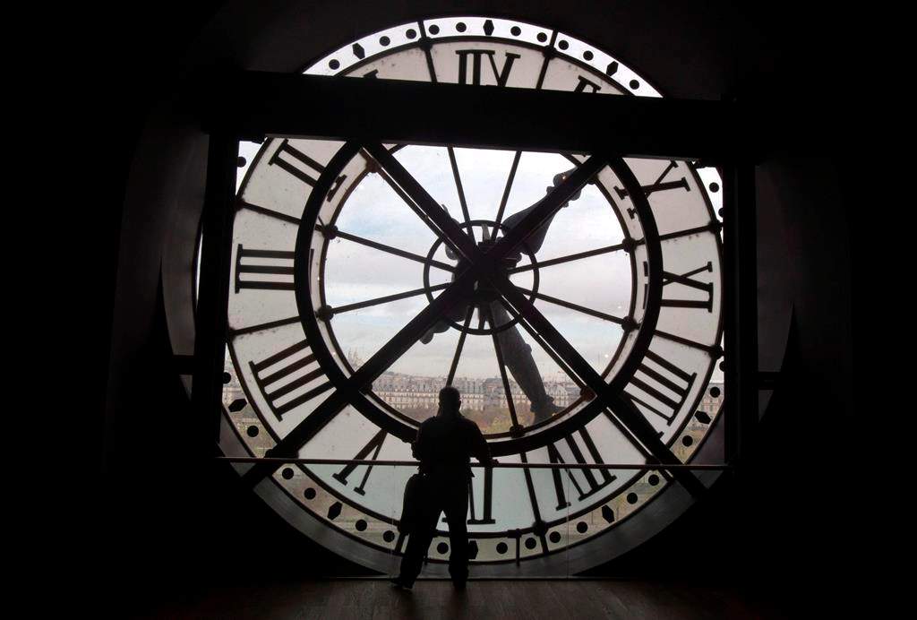 A visitor looks through the clock of the Orsay museum, overlooking Paris, Thursday, Oct. 16, 2014. THE CANADIAN PRESS/AP, Michel Euler