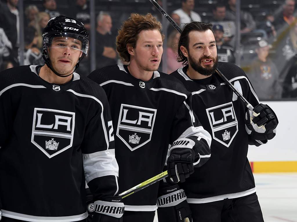 (L-R) Dustin Brown #23, Tyler Toffoli #73 and Drew Doughty #8 of the Los Angeles Kings talk during warm-up before the game against the Vegas Golden Knights at the Staples Center on Oct. 13, 2019 in Los Angeles, Calif.