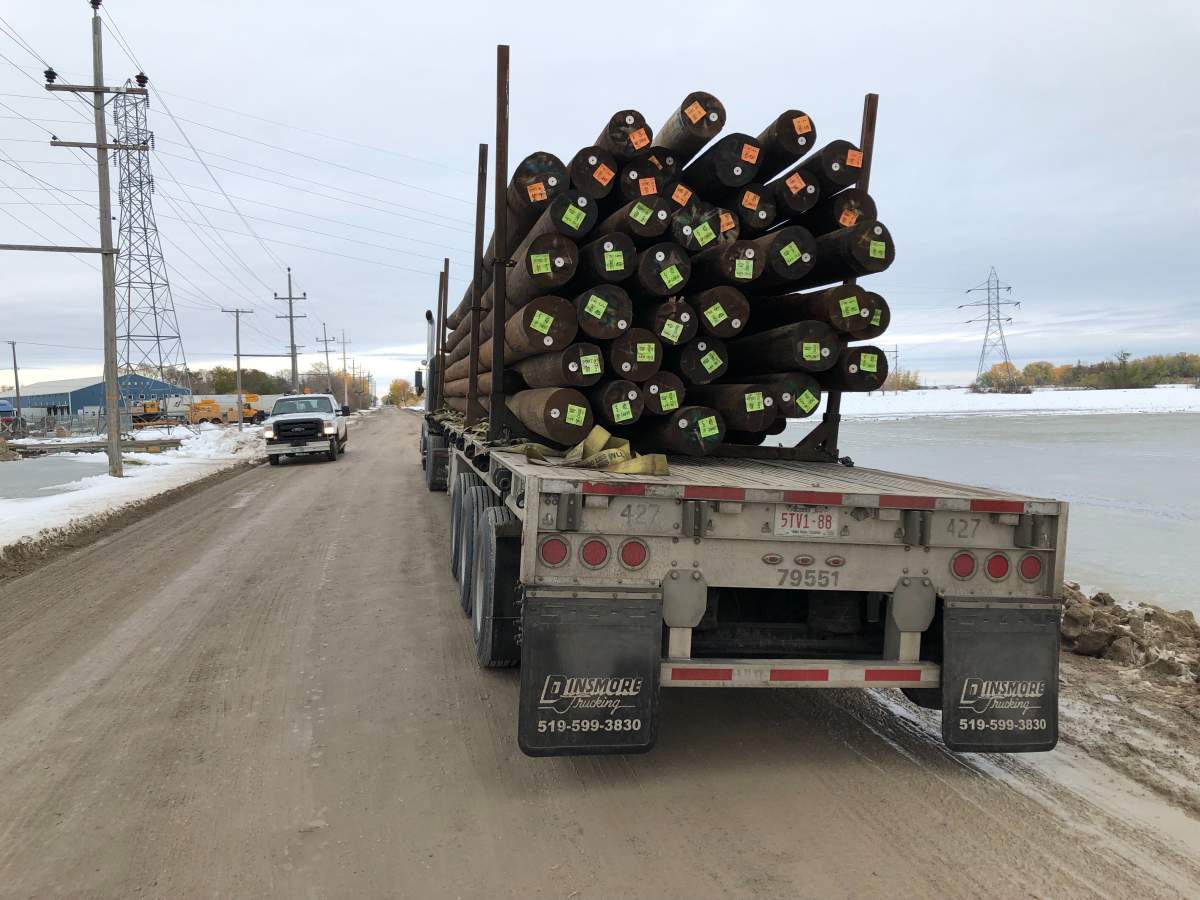Hydro poles from Regina are hauled into Portage la Prairie on an Alberta flatbed truck.