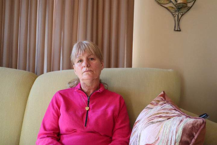 Kathleen Coombs sits on her couch at her Penetanguishene, Ont. home, wearing a locket that holds her son's ashes. He was murdered in Alberta earlier this year.