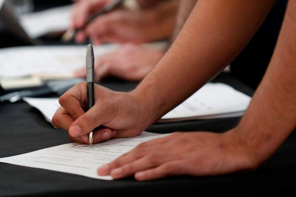 FILE - In this Oct. 1, 2019, file photo job seekers fill out applications during a job fair at Dolphin Mall in Miami.