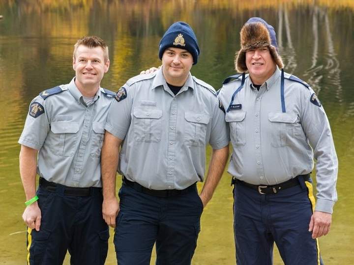 RCMP Cpl. Mike Esson, left, Const. Josh McCann and Cpl. Thomas Blakney, each of the Revelstoke detachment, stand together before plunging into the freezing cold waters of Williamson Lake, seen in the background.