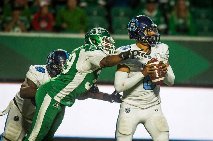 Saskatchewan Roughriders defensive lineman Charleston Hughes tries to strip the ball from Toronto Argonauts QB James Franklin in Regina on July 1, 2019.