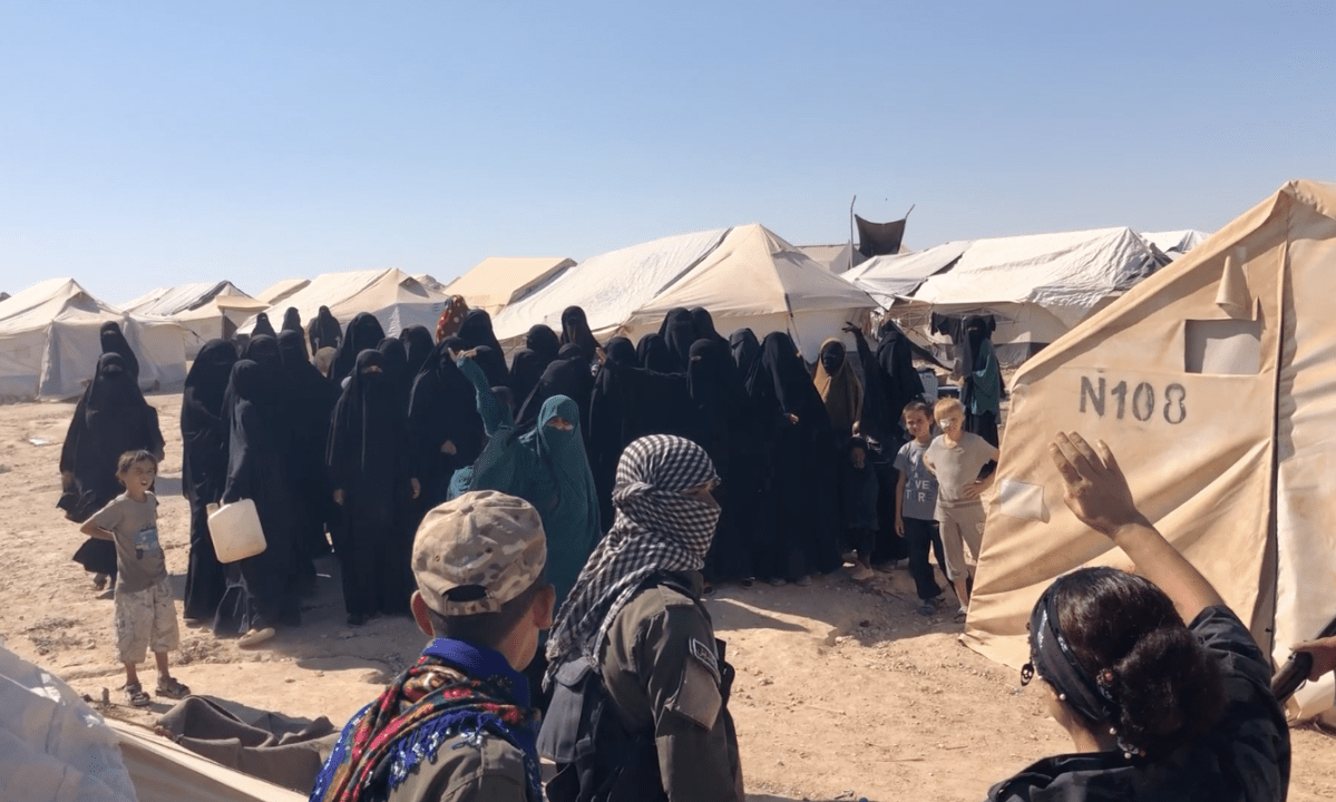 At Al-Hawl camp in northern Syria, children watch as women confront Kurdish guards in a confrontation that quickly turned violent.
